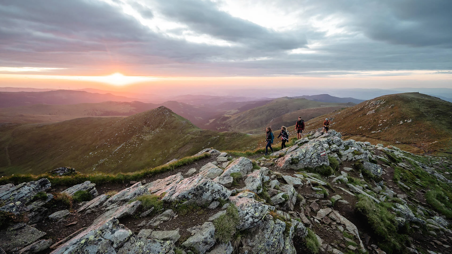 Wanderer erleben den Sonnenuntergang auf der Koralpe